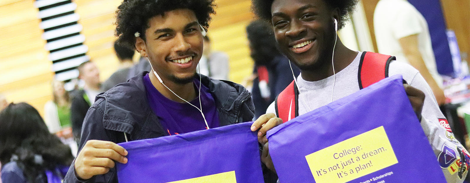 Two students holding up college drawstring bags.